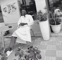 a man sitting on a chair in front of a potted plant