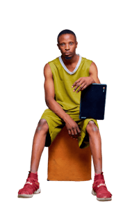 a young man sitting on a stool holding a laptop